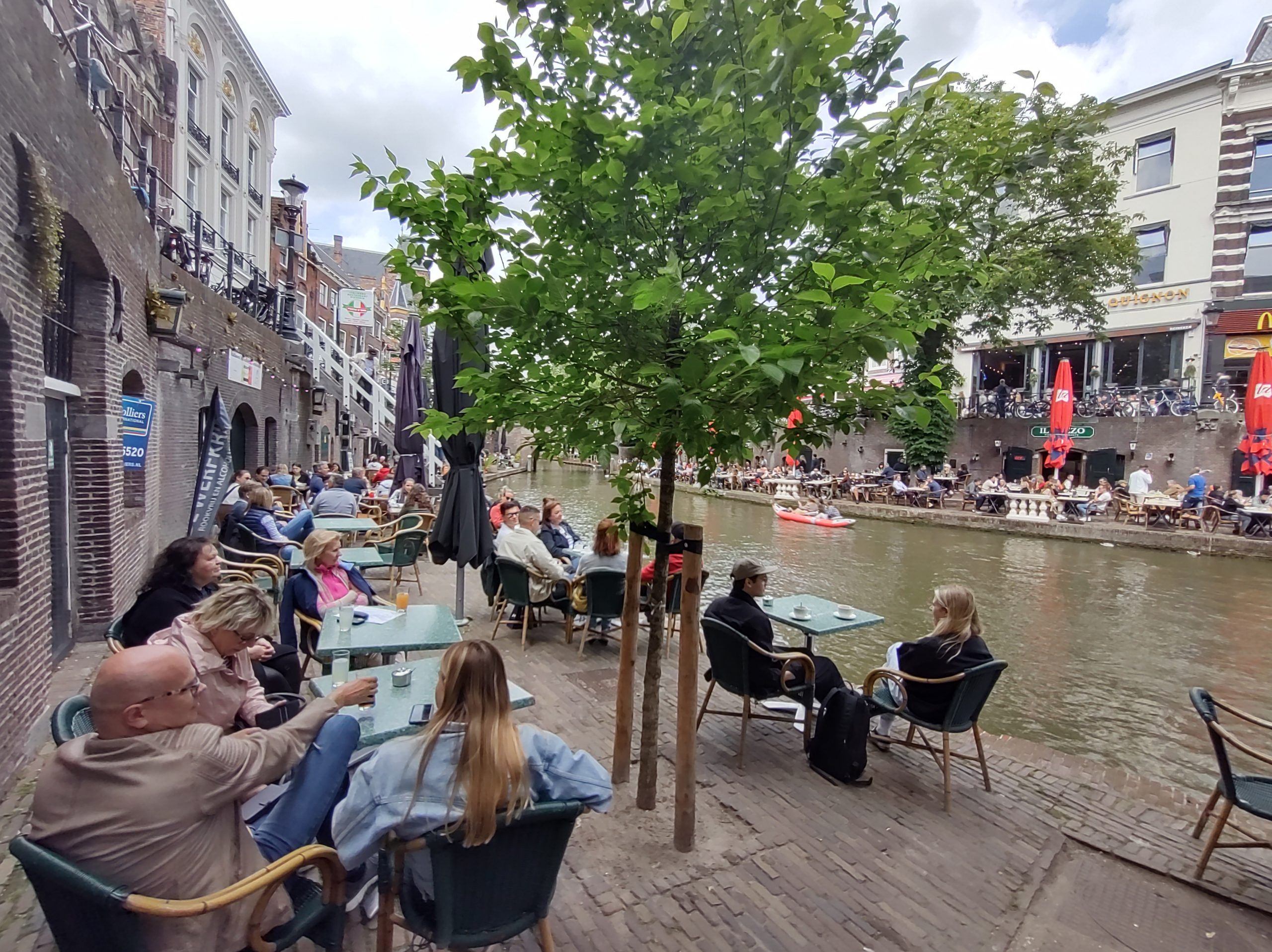 Een drukbezocht terras door gasten met diverse leeftijden.